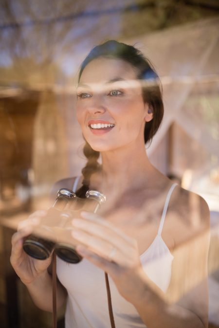 Beautiful woman holding binoculars during safari vacation